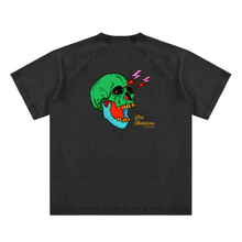 Load image into Gallery viewer, A light beige short-sleeve raglan t-shirt featuring a colorful graphic of a green skull with yellow teeth, lightning bolts, and a blue dotted pattern on the chest, with 'Pop America' text printed below.
