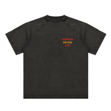 Load image into Gallery viewer, A washed black short-sleeve raglan t-shirt with 'SUPPORT LO-CAL ART' printed in reddish orange and yellow on the left chest, displayed on a clean white background.
